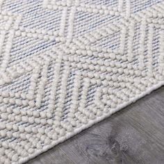 an area rug with white and blue designs on it, sitting on top of a wooden floor