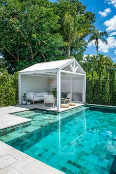 a swimming pool with a gazebo next to it and lounge chairs on the side