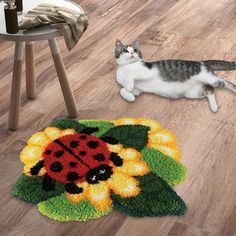 a cat laying on the floor next to a rug with a ladybug design