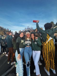 three girls are posing for the camera with their arms in the air and one girl is holding up a red cup