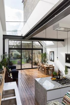 an open kitchen and dining area with wooden floors, glass walls, and sliding doors