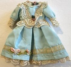 a doll is dressed in blue and white with laces on the collar, dress