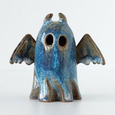 a blue ceramic figurine with two holes in it's mouth and wings