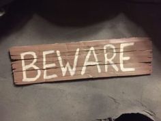 a wooden sign that says beware sitting on top of a black table next to a pair of shoes