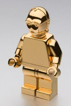 a gold lego figure is standing on a white surface with one hand in the other's pocket