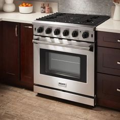 a stove top oven sitting inside of a kitchen next to wooden cabinets and counter tops