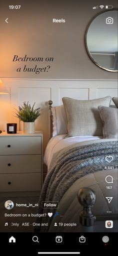 a bed room with a neatly made bed and a round mirror on the wall above it