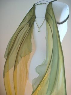 a green and yellow scarf on a mannequin's head with a necklace hanging from it