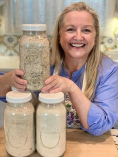 a woman is holding two jars full of food