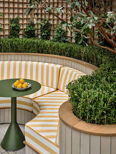 an outdoor seating area with yellow and white striped seats, round table and potted plants