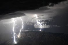 two lightning strikes in the sky over mountains