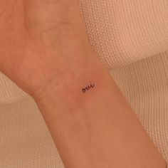 a woman's wrist tattoo with the word ouu written in cursive writing