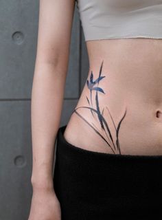 a woman's stomach with blue flowers tattooed on her lower body and the bottom part of her belly