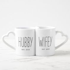 two white coffee mugs with the words hubby and wife printed on them sitting next to each other