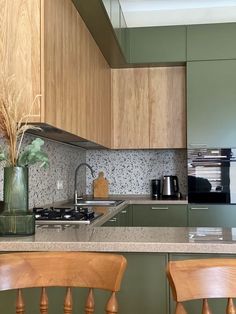 a kitchen with green cabinets and wooden stools