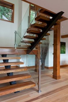 a wooden stair case with glass railing and wood flooring in a modern style home