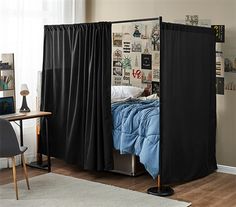 a bedroom with a bed covered in black drapes next to a desk and chair