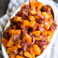 bacon and sweet potatoes on a white platter with a striped towel in the background