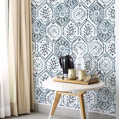 a small table with some items on it in front of a wallpapered room