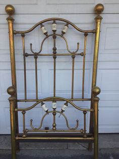 a gold metal bed frame with four candles on it's headboard and foot board