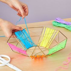 the person is making a sculpture out of colored sticks