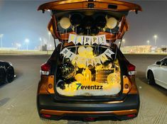 an open trunk of a car with balloons and decorations on the back, in a parking lot at night