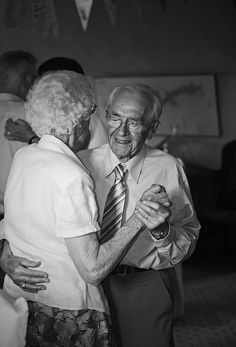 two elderly people dancing together in a room