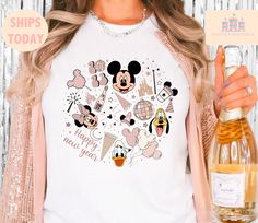 a woman holding a bottle of wine and wearing a mickey mouse t - shirt that says happy new year