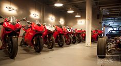 a row of red motorcycles parked in a parking garage next to each other on wheels