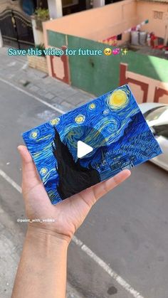 someone is holding up a piece of art that looks like the starry night painting