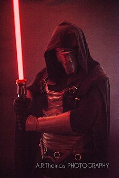 a man dressed as darth vader holding a light saber