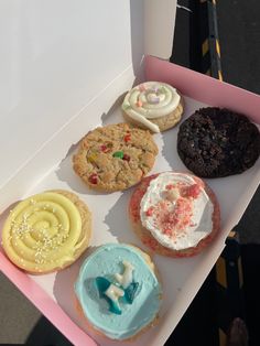 a box filled with lots of different flavored donuts on top of a table