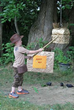 a young boy holding a stick in front of a bird feeder