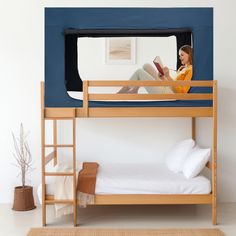 a woman sitting on top of a bunk bed next to a blue tent with a ladder