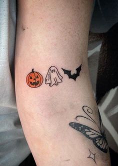 a person with a tattoo on their arm that has two pumpkins and a ghost