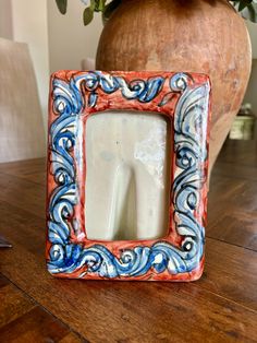 a ceramic photo frame sitting on top of a wooden table next to a potted plant