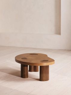 a wooden table sitting on top of a hard wood floor next to a white wall