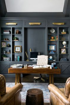 a home office with built - in bookcases and leather chairs, along with a desk