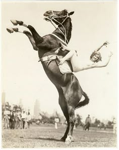 a woman riding on the back of a horse in an old fashioned photo with people watching