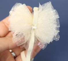 a hand holding a small white bow with sequins on it's side