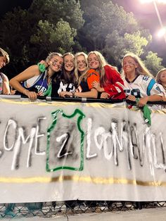 a group of young women standing behind a banner