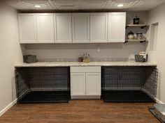 an empty kitchen with white cabinets and black dog kennels