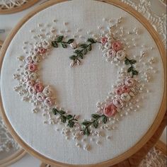 an embroidered heart with flowers and leaves in the middle is surrounded by other handmade items