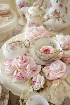 a table topped with pink roses and tea cups