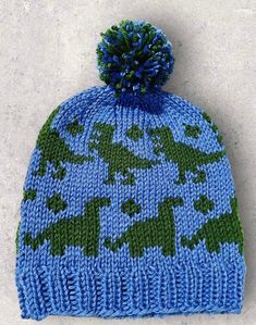 a blue and green knitted hat with trees on it, sitting on the ground