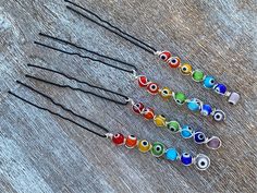 QUICK DETAILS Item: Rainbow Evil Eye hair pin  Colors: Red, orange, yellow, green, blue purple, silver, black, white Material: Metal, glass Size: ~4.5 inch (from pin tip to bead tip) Lot Sizes: 1 pin or Set of 10 Hand crafted, tiny rainbow evil eye themed hair pins. The metal pin has a wire wrapped evil eye bead in red, orange, yellow, green, blue and purple dangling down from a black hair pin. They're perfect to add to your updo, pony tail or bun hairstyles.  * You can choose from gold, silver Braid Jewelry Hair Accessories, Silver Hair Jewelry, Rainbow Evil Eye, Hair Accessories Silver, Bead Tips, Jewelry Hair Accessories, Braid Jewelry, Wire Wrapped Crystal, Loc Jewelry