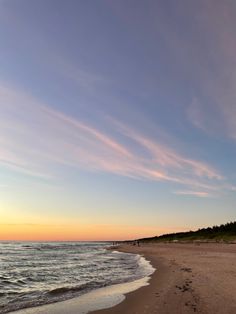 the sun is setting at the beach with footprints in the sand