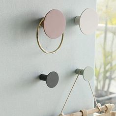 three circular knobs are mounted on the wall next to a curtain rod and some rope