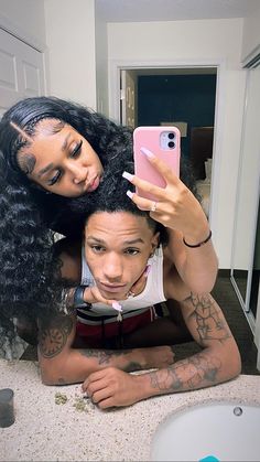 a woman taking a selfie with her friend in front of a bathroom sink and mirror