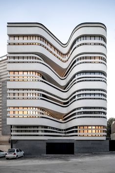 an unusual building in the middle of a parking lot with cars parked on the side